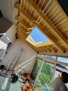 Chantier Applitech Enveloppe à Béthune montrant la transformation d'une véranda. Pose d'une charpente traditionnelle en bois massif avec chevêtre intégré pour accueillir une future verrière de toit. La structure bois renforce l'isolation de cette extension de maison.