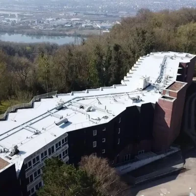 Vue aérienne de la réhabilitation thermique de la toiture de l’ehpad des Hautes Bruyères à Bonsecours, avec la seconde couche d’étanchéité en cours de pose par Applitech Enveloppe.