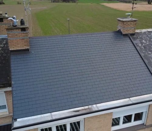 Vue aérienne de maisons mitoyennes à Linselles ; au centre, la toiture après intervention Applitech Enveloppe, avant équipement de panneaux solaires photovoltaïques, comparée visuellement aux toits voisins sans panneaux (avant/après).