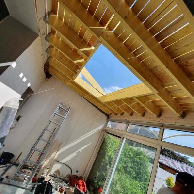 Chantier Applitech Enveloppe à Béthune montrant la transformation d'une véranda. Pose d'une charpente traditionnelle en bois massif avec chevêtre intégré pour accueillir une future verrière de toit. La structure bois renforce l'isolation de cette extension de maison.